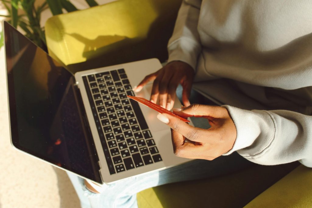 Person holding a credit card and using a laptop, representing online customer data interaction for personalized marketing.